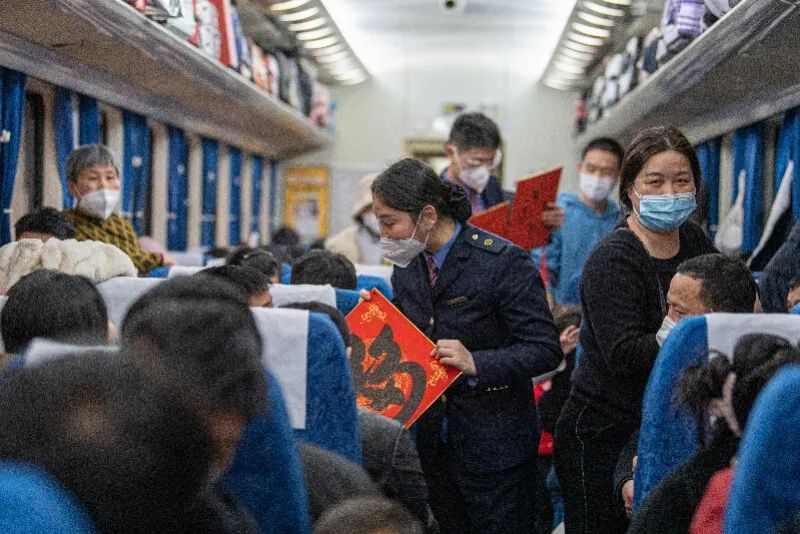 K209次列车的工作人员在车厢内向旅客赠送新春福字